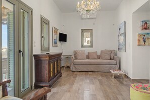 A living room with a wooden cabinet, a beige sofa, a small table, and a television.