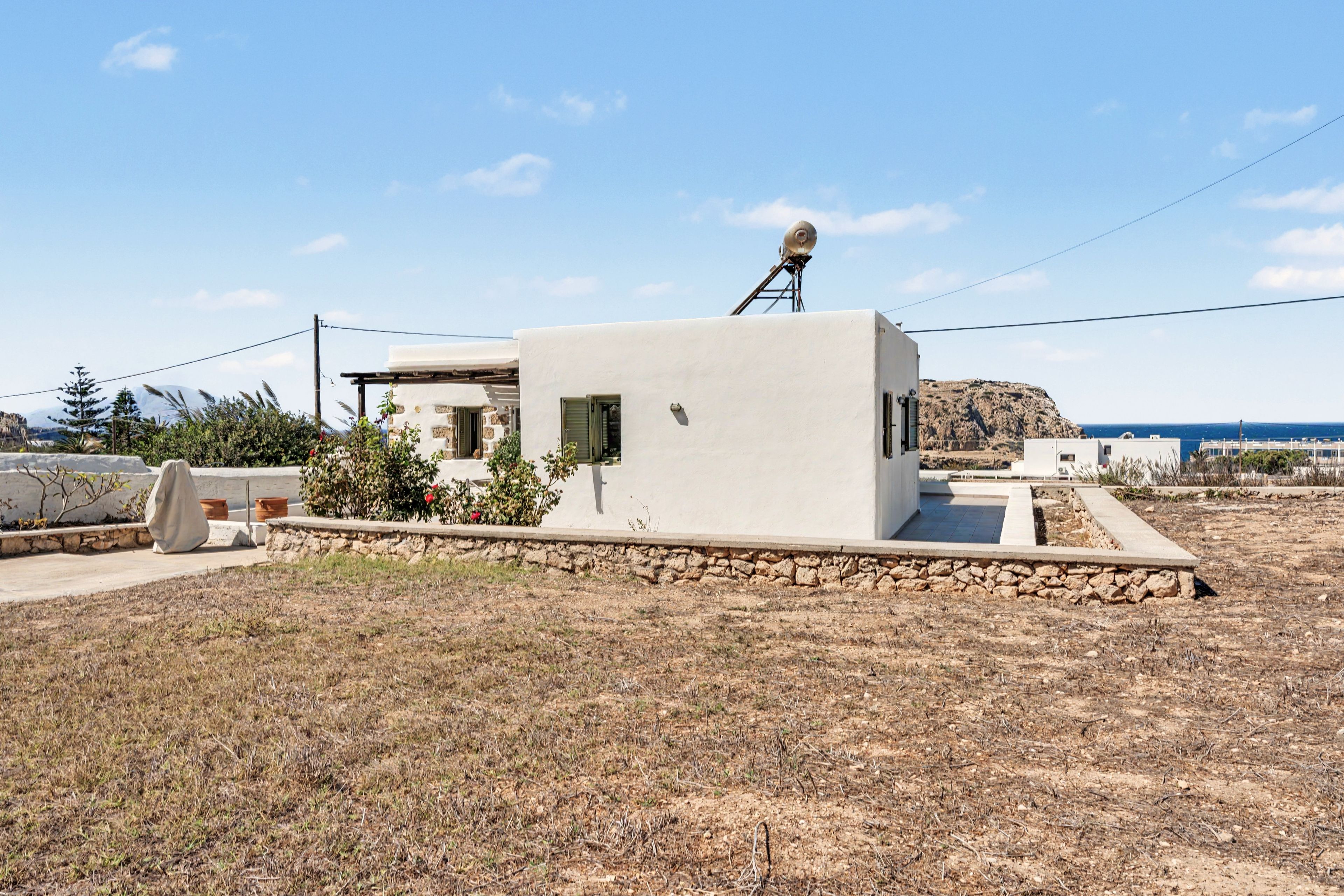 Un bâtiment moderne, de plain-pied, doté d’un toit plat, d’une antenne parabolique sur le toit et de fondations en pierre.