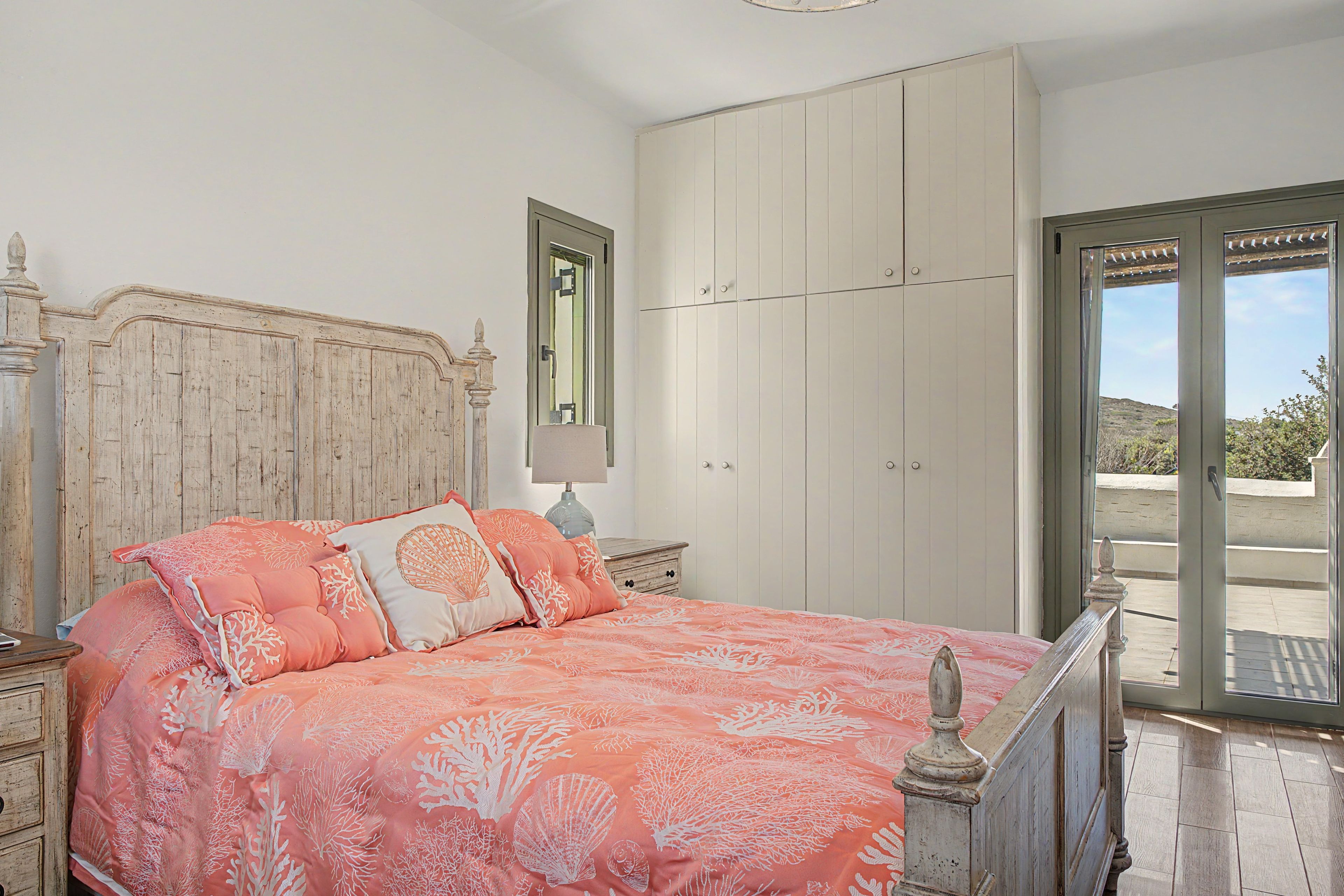 A bedroom with a bed, a wardrobe, a nightstand, and a window.