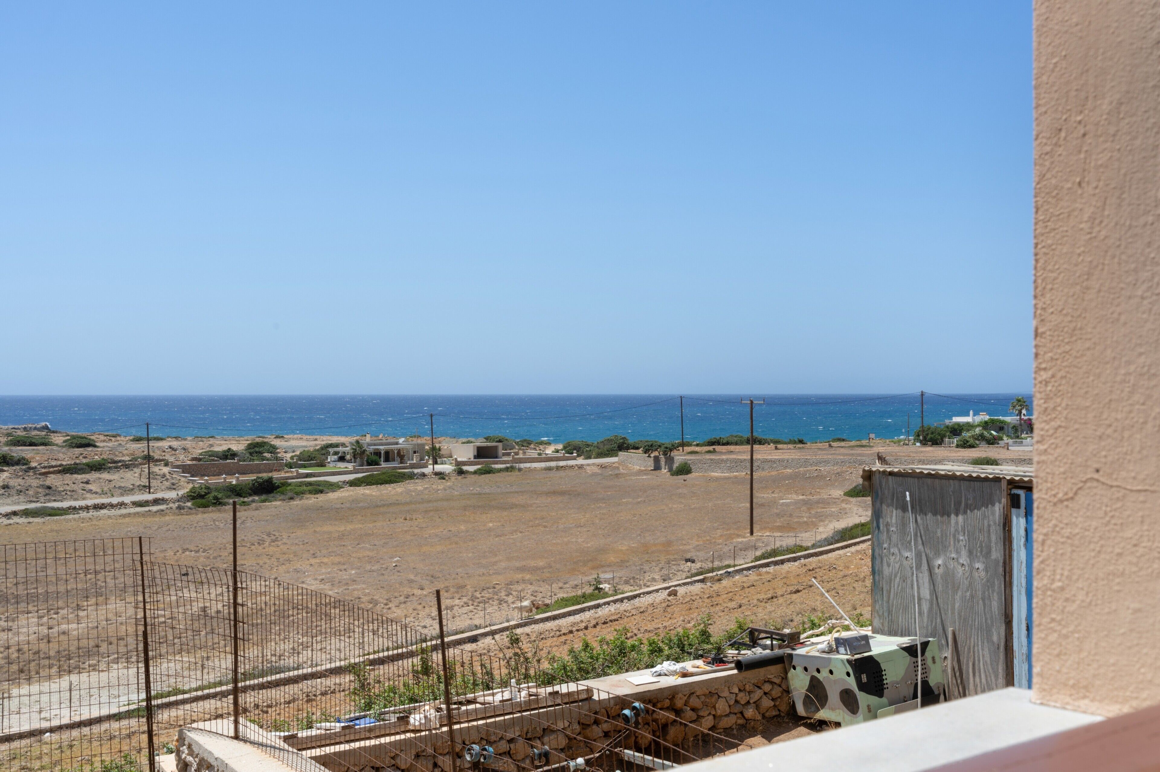 A view of a coastal area with a clear sky, a sandy beach, and a distant body of water.