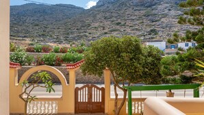 Un balcón con vistas a un paisaje montañoso, una reja y un pequeño árbol.