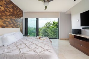 Ein modernes Schlafzimmer mit einem großen Bett, einem Deckenventilator, einem Fernseher und einem Balkon mit Blick auf die Stadt.