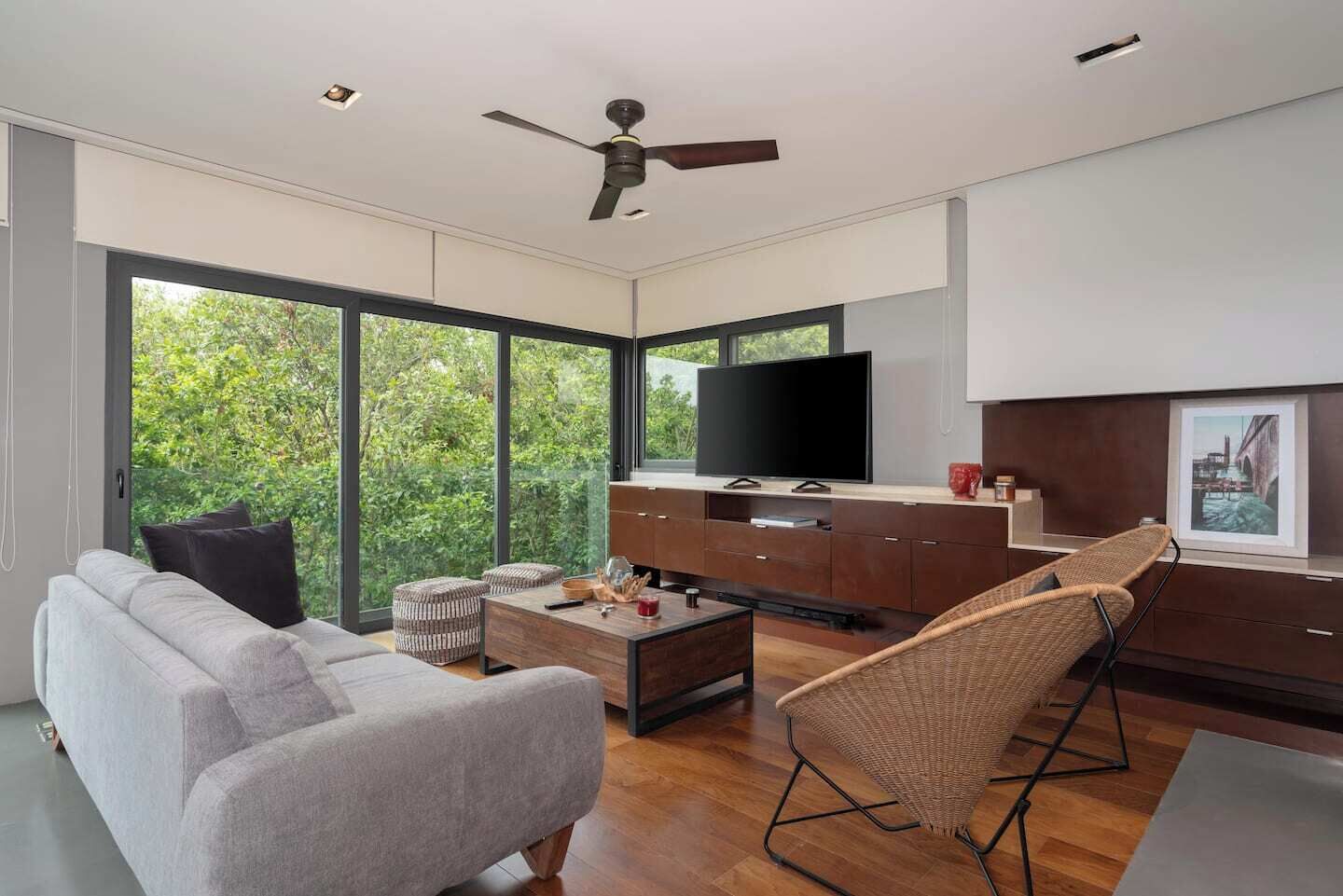 Een moderne woonkamer met een bank, salontafel, televisie en rieten stoelen.
