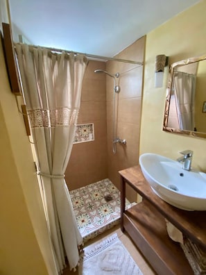 Une salle de bain avec une douche, un lavabo, un miroir et des carreaux décorés.