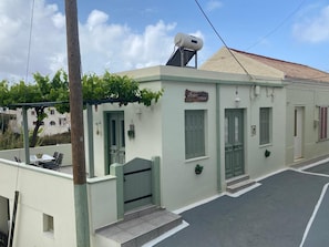 A building with a green door, a small outdoor seating area, and a sign that reads 'Ava's Studios.'