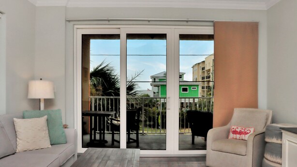 A room with a sofa, armchair, and a table with chairs. There is a sliding glass door leading to an outdoor area with a table and chairs. - ☀️ Short Walk to Beach - Summerhouse 206 – Brown Eyed Girl ☀️ (Mexico Beach)