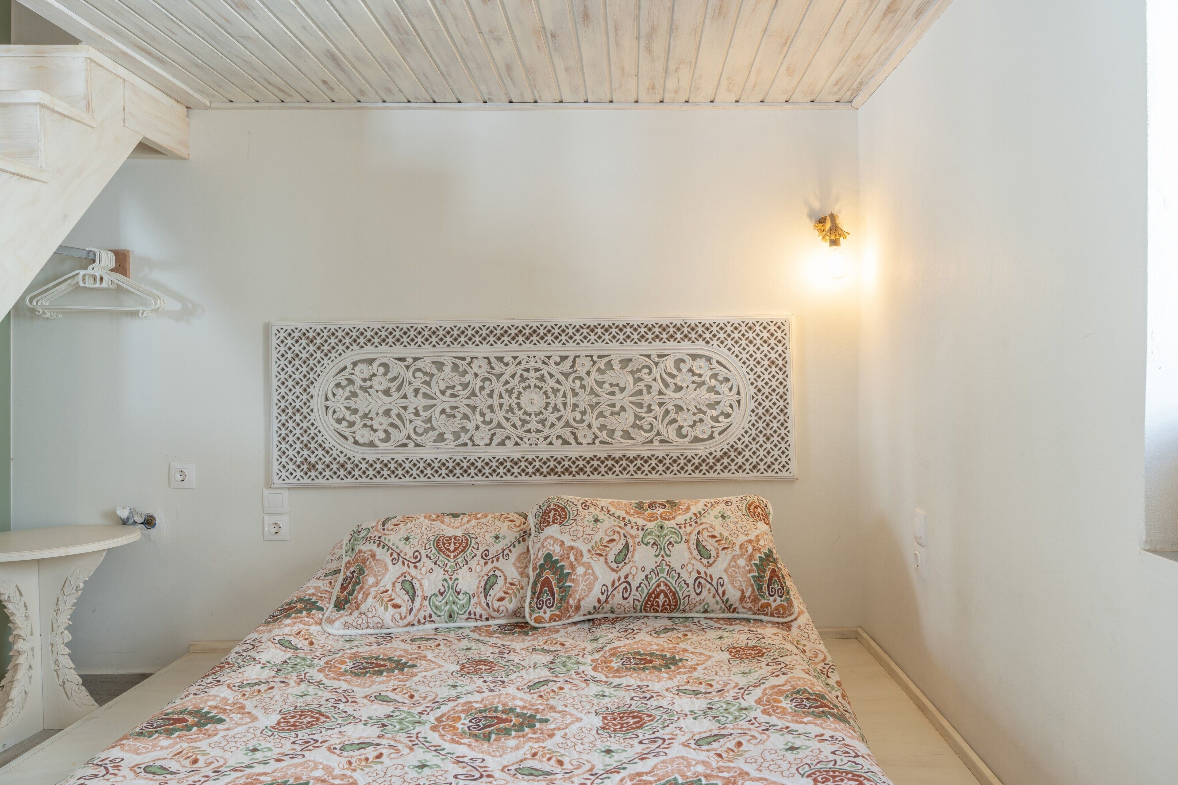 A bedroom with a bed, a wall-mounted decorative piece, and a light fixture.