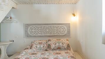 A bedroom with a bed, a wall-mounted decorative piece, and a light fixture.