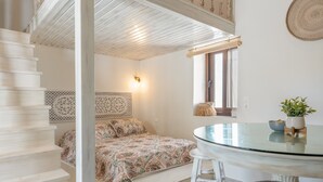 Ein Schlafzimmer mit einem Bett, einem Glastisch, einem Stuhl, einer Treppe und einer Wand mit einer Zierverkleidung.