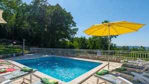 A swimming pool with lounge chairs and an umbrella.
