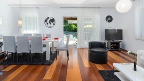A modern living room with a dining area, a TV, and a view of the outdoors.