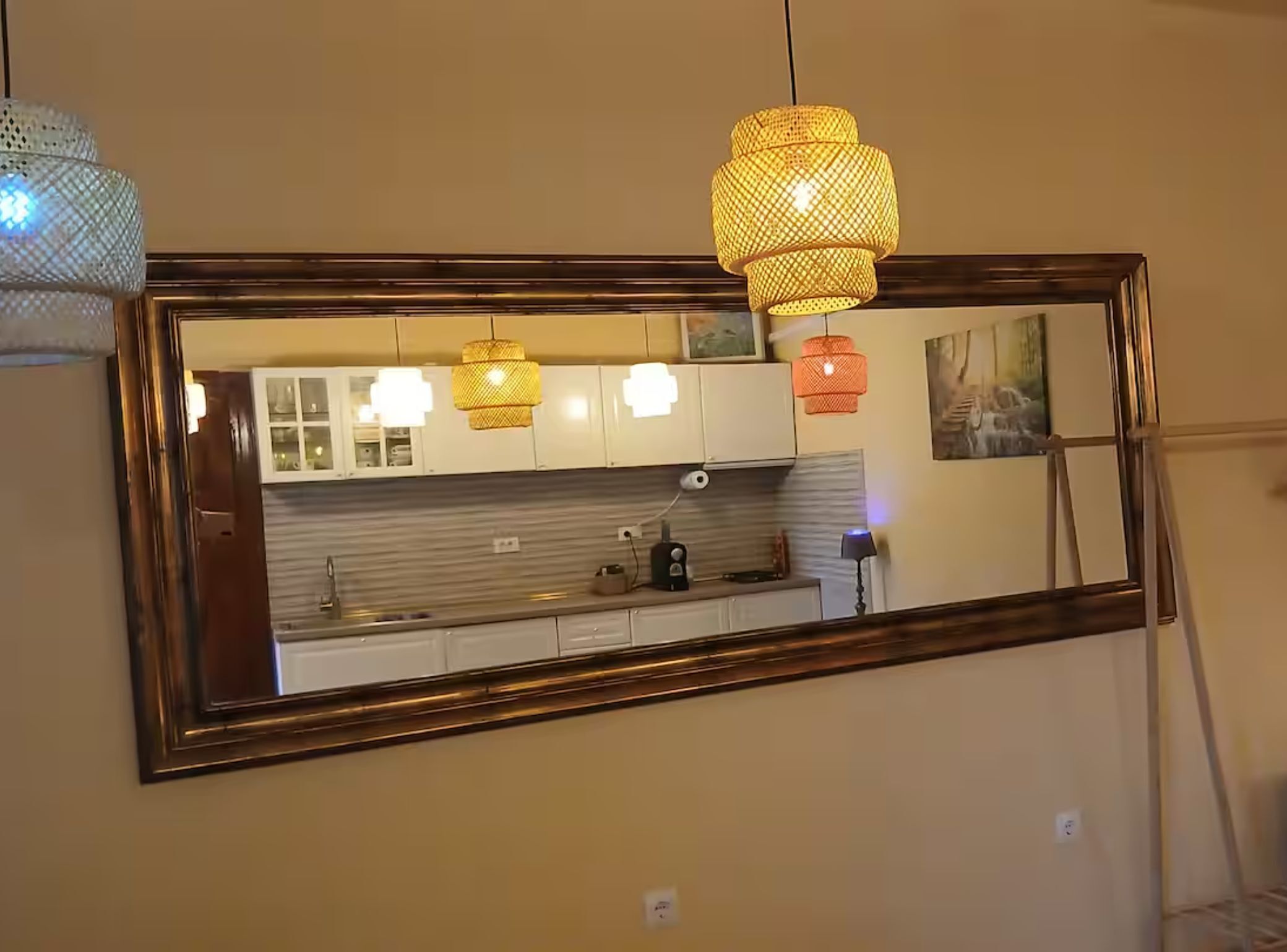 A kitchen with a large mirror, wooden cabinets, and pendant lights.