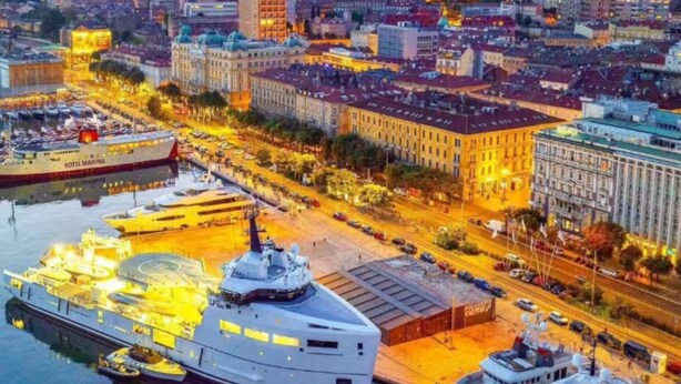 Ein Yachthafen mit vertäuten Yachten, ein großes Gebäude mit Kuppel und eine Stadtansicht mit Gebäuden und Straßen.