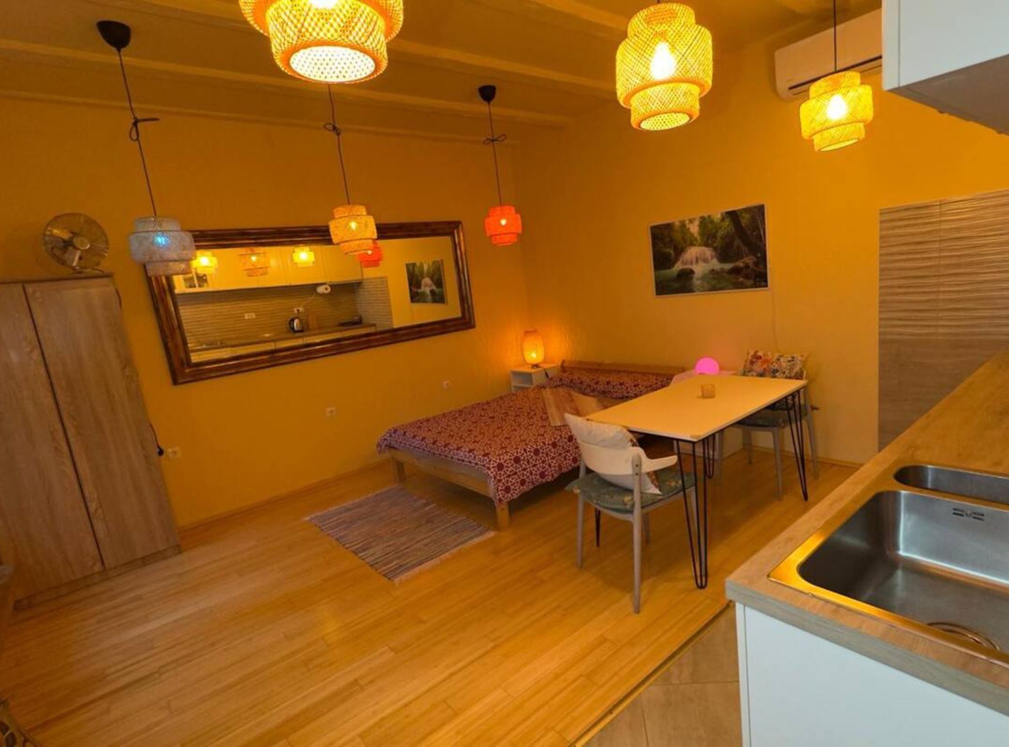 A compact kitchen with a dining area, a small sofa, and a wooden cabinet.