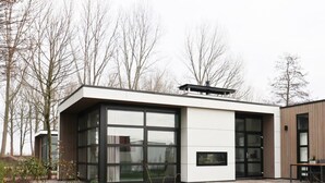 A modern house with large glass windows, a flat roof, and a patio area. - Holiday Home in Nijkerk With Terrace (Nijkerk)