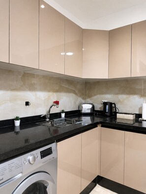 A modern kitchen with a washing machine, a toaster, and a kettle. - Modern 2-Bedroom Apartment in Central Gueliz Near Carré Eden (Marrakesh)