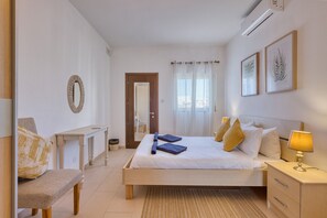 Ein Schlafzimmer mit Bett, Nachttisch, Lampe und Blick ins Freie.
