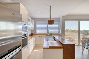 Eine moderne Küche mit einem Edelstahlkühlschrank, einer Holzarbeitsplatte und Blick auf den Balkon.
