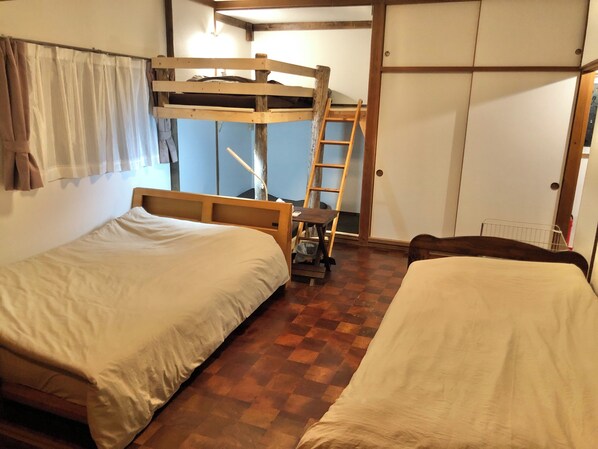 Una habitación con dos camas, una litera de madera, una escalera, un escritorio y un armario.