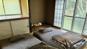 A room with two beds, a small table, and a view through large windows.