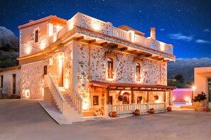 Ein Gebäude aus Stein mit Balkon, Treppe und einer Veranda mit Blumentöpfen.