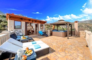 Eine Terrasse mit Sitzgelegenheiten im Freien, einem Whirlpool und einem Boden aus Steinplatten.