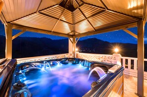 Ein Whirlpool unter einem Holzdach mit Blick auf den Nachthimmel.