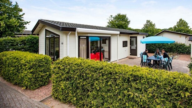 A modern house with a patio area, a dining table, and a blue umbrella. - Holiday Home for 5 People (Noordwijk)