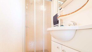 A bathroom with a shower, a sink, and a mirror. - Holiday Home for 5 People (Noordwijk)