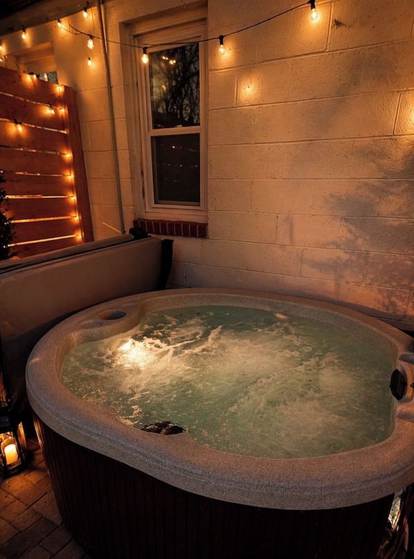 Un jacuzzi con revestimiento de piedra, rodeado por un muro de ladrillo y una ventana.