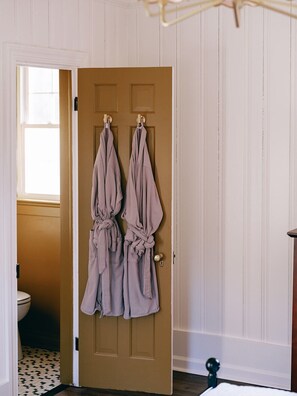 Una habitación con puerta de madera, ventana y vista al baño.