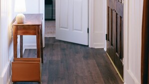 A hallway with a wooden bench, a lamp, and a door with a window.
