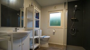 A bathroom with a sink, toilet, shower, and a window with frosted glass. - Holiday Home in Velsen-zuid With Terrace (Velsen-Zuid)