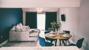 Una sala de estar moderna con sofá, mesa de comedor, sillas y una araña.