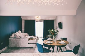Ein modernes Wohnzimmer mit Sofa, Esstisch, Stühlen und einer Chandelier.