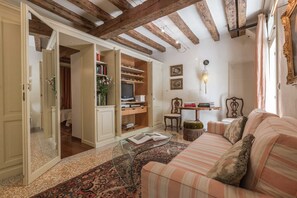 A cozy living room with a sofa, a coffee table, and a bookshelf. - Elegant Venetian Home with Private Courtyard in the Heart of Dorsoduro (Venezia)