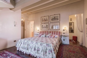 Ein Schlafzimmer mit einem blumigen Bettüberwurf, einem rot-gestreiften Kopfteil und einem großen Spiegel.