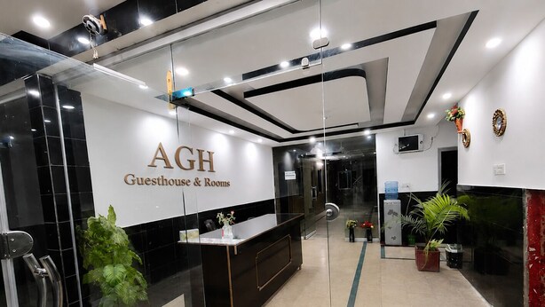 Een moderne hotellobby met een receptiebalie, glazen scheidingswanden en potplanten.