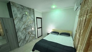 Ein Schlafzimmer mit Bett, Kleiderschrank, Wand mit Marmoroptik und Deckenleuchte.