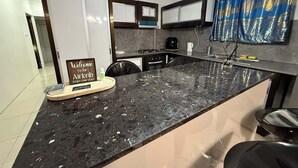 Eine moderne Küche mit Marmorarbeitsplatte, einer Kaffeemaschine und einem Schild, das Gäste zum Airbnb willkommen heißt.