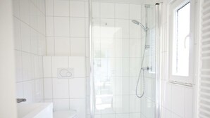 A bathroom with a glass-enclosed shower, a toilet, and a sink. - Cube Exclusive 4 (Velsen-Zuid)