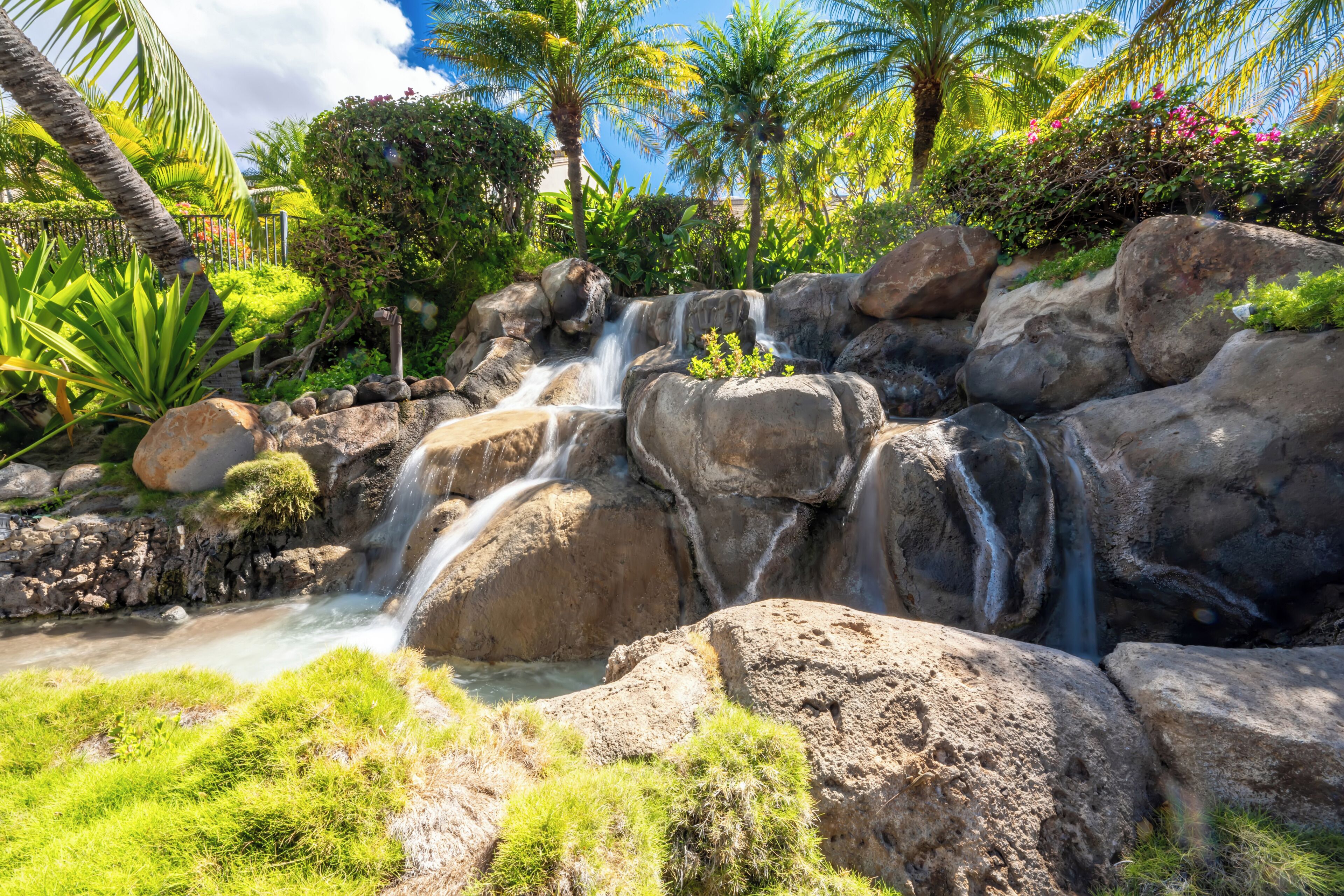Een waterval omringd door grote rotsen en weelderige begroeiing.