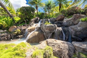 Ein Wasserfall, umgeben von großen Felsen und üppigem Grün.