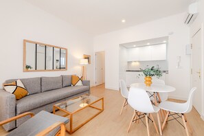 Een moderne woonkamer met een bank, salontafel en een eethoek met stoelen.