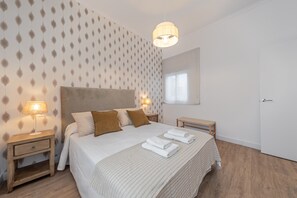 Een slaapkamer met een bed, nachtkastjes, een hanglamp, een raam en een deur.