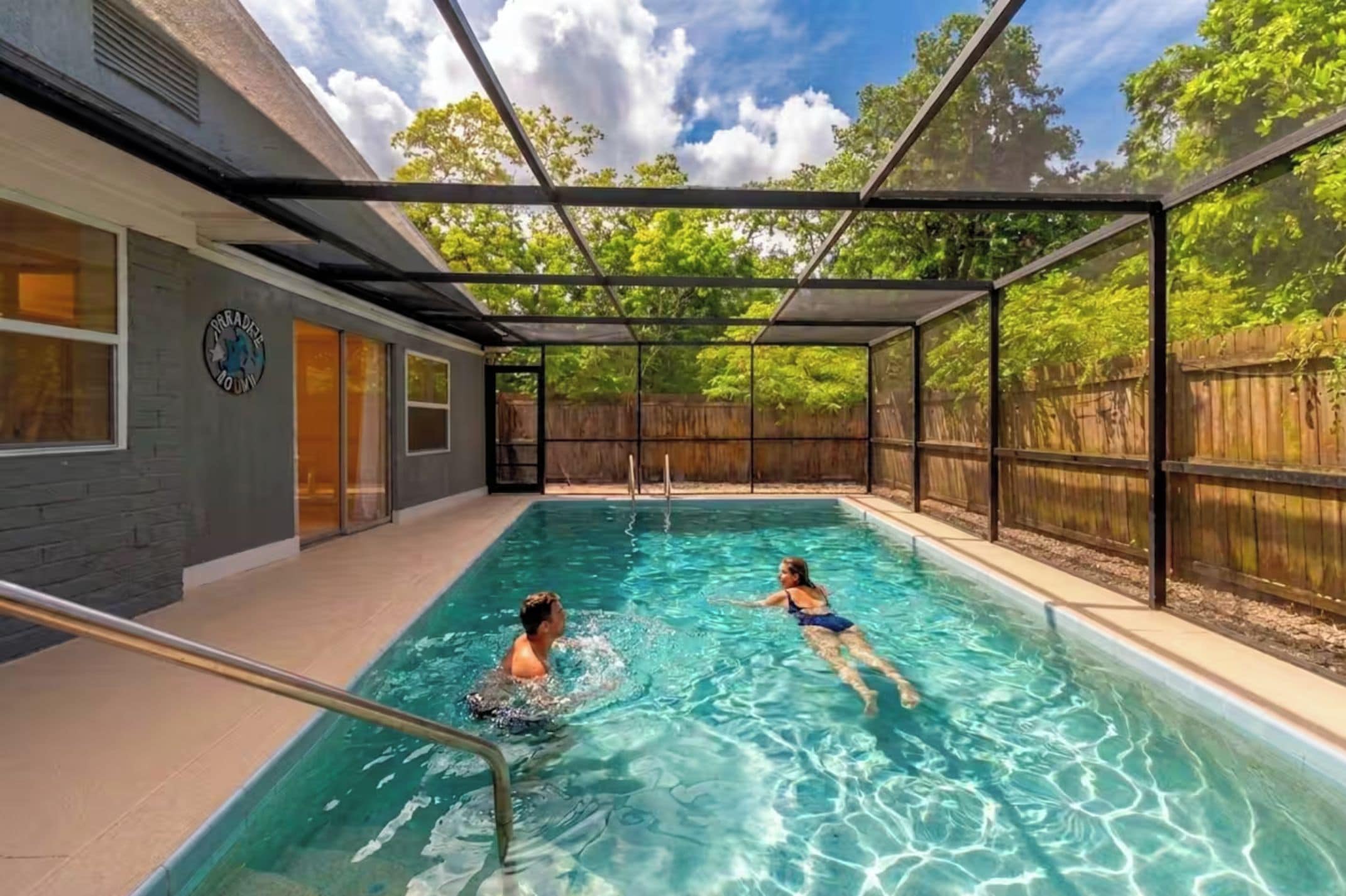 An indoor swimming pool with clear water, surrounded by a covered area with a wooden fence.