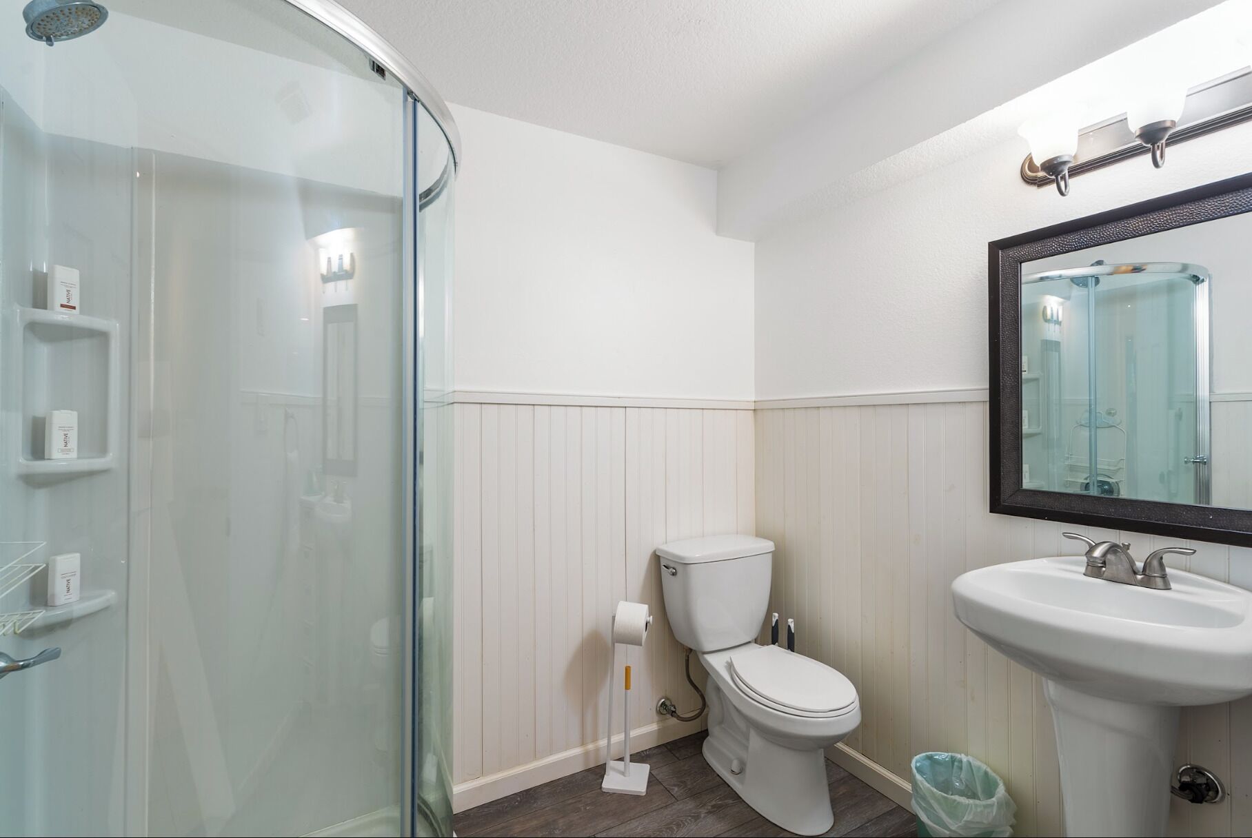 Een badkamer met een douchecabine van glas, toilet en wastafel.