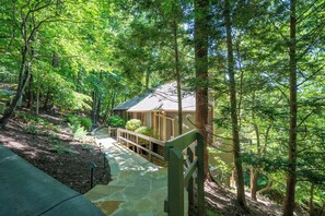 Eine Hütte, umgeben von dichtem Wald, mit einem Steinweg, der zum Eingang führt.