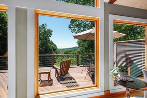 Eine Terrasse mit Holzmöbeln, einem Tisch und einem Stuhl mit Blick auf eine reizvolle Landschaft.