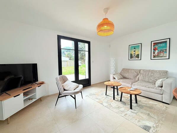Ein Wohnzimmer mit Fernseher, Sofa, Sessel, Couchtisch und einem großen Fenster mit Blick.